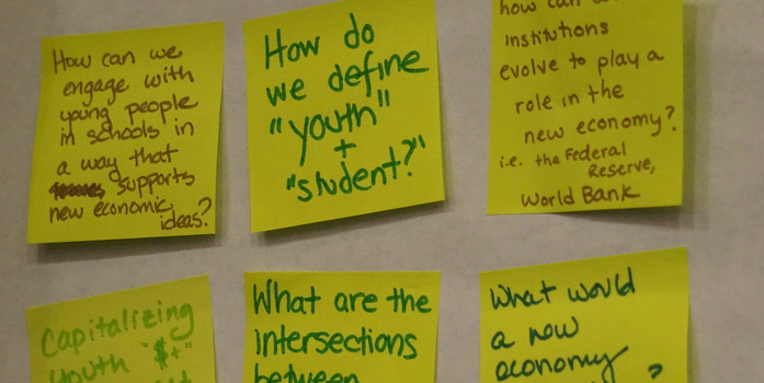 6 yellow Post-It notes affixed to a wall, each with a hand-written question about the new economy