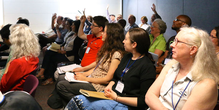 Audience at a workshop at CommonBound 2014. Some people have their hands raised to ask a question.