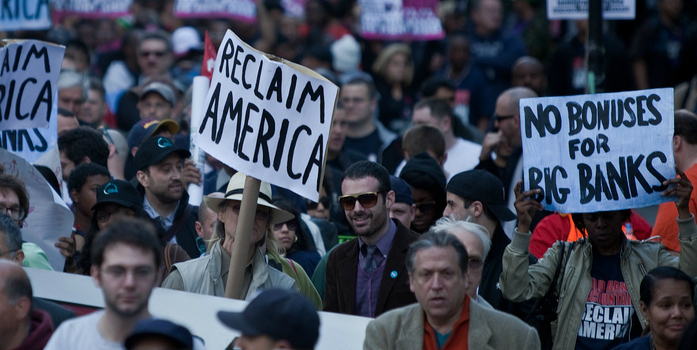 A large rally. People are holding up signs, the most prominent of which read "Reclaim America" and "No Bonuses for Big Banks" 